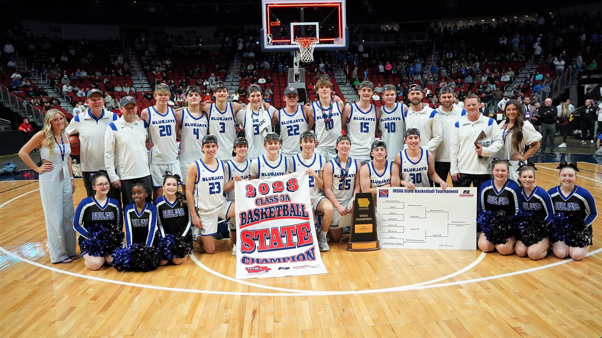 Team photo of players, coaches, cheerleaders, and managers with champion banner and trophy